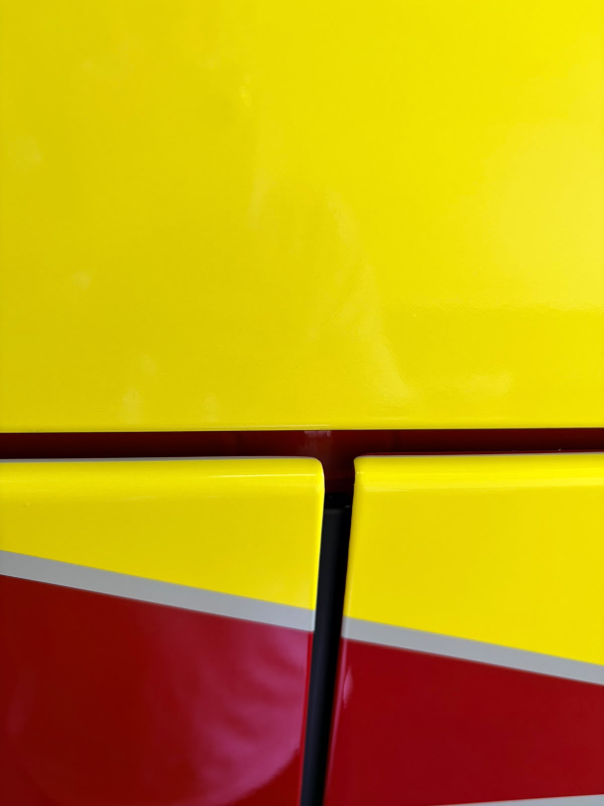 Nahaufnahme einer gelb-roten Fahrzeugfolierung mit reflektierendem Streifen
