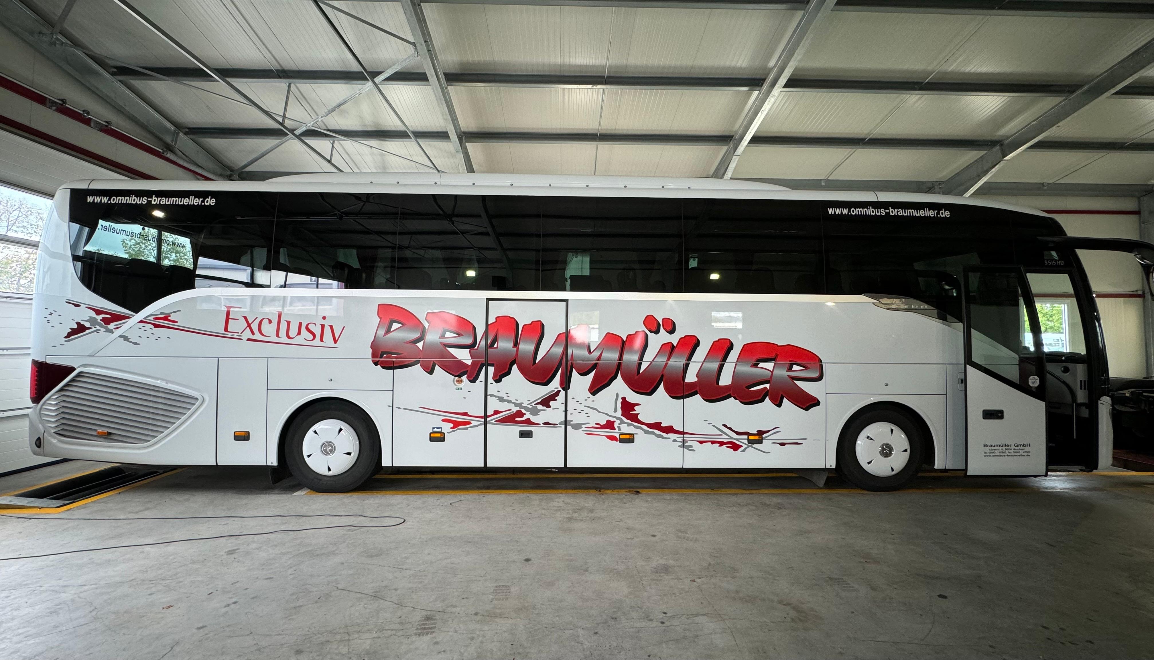 Weißer Reisebus von Braumüller mit großer rot-grauer Seitenbeschriftung
