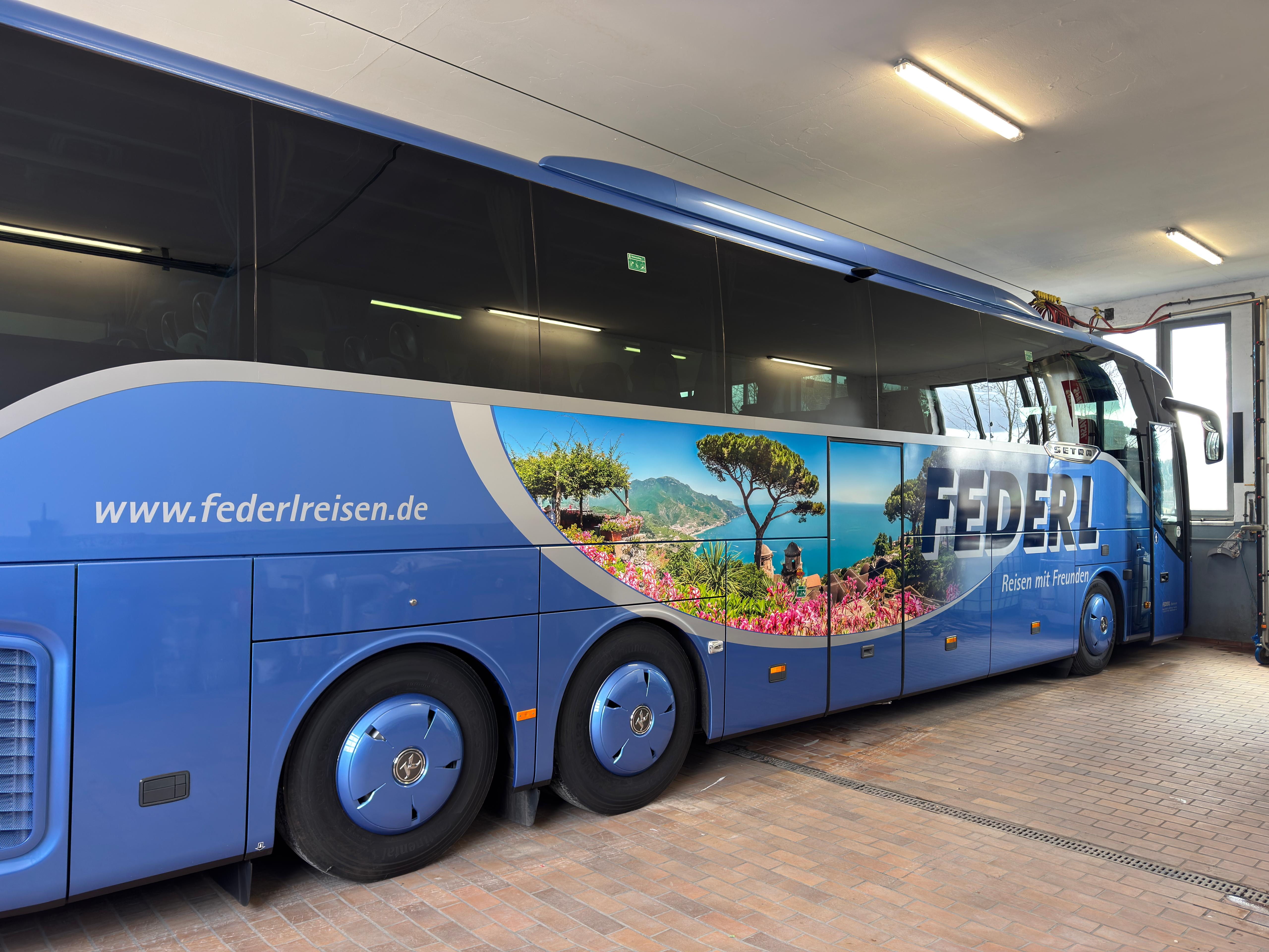 Blauer Federl-Reisebus mit großformatigem Küstenpanorama in der Werkstatt