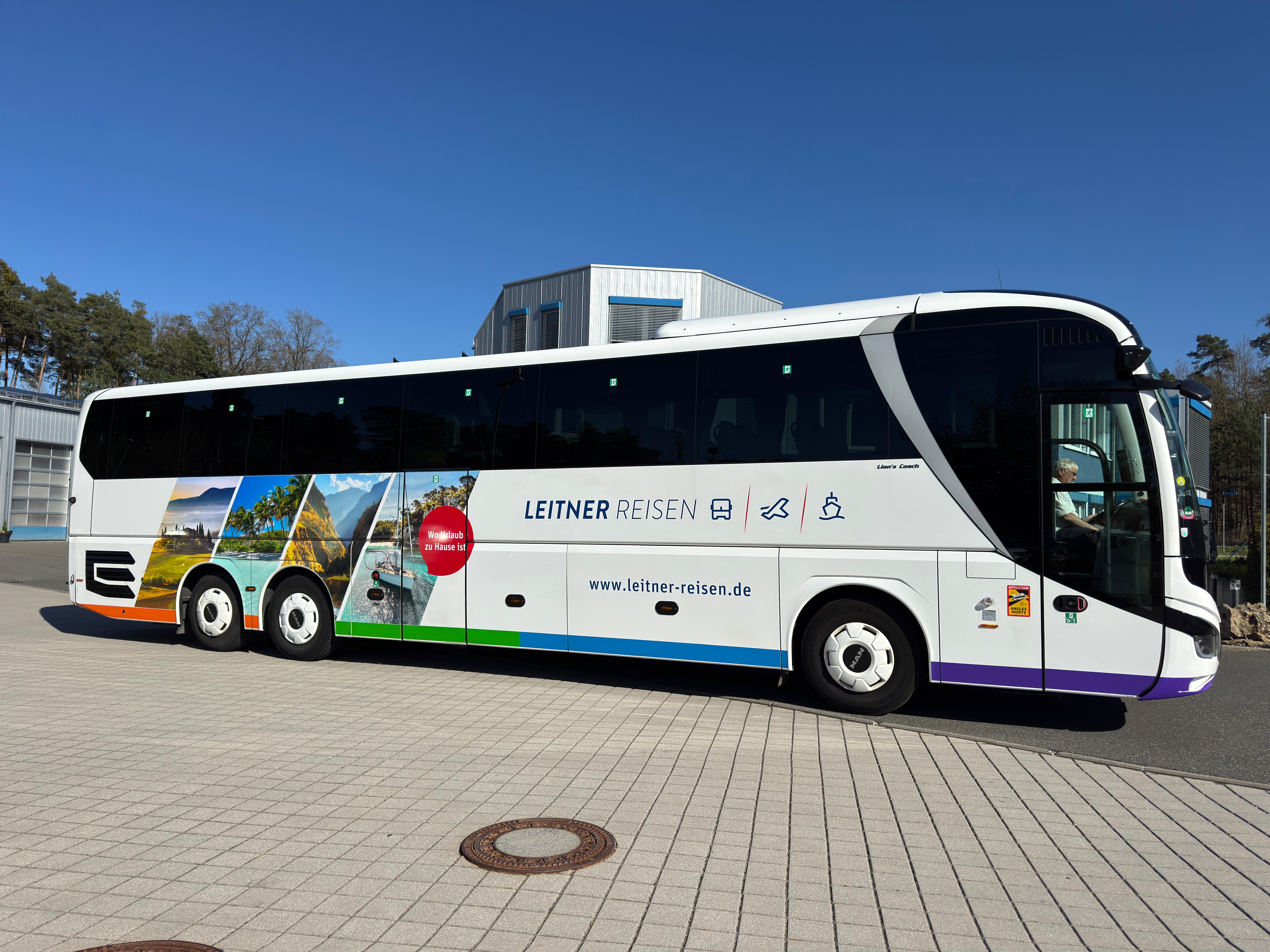 Weißer Reisebus von Leitner Reisen mit farbigen Urlaubsmotiven