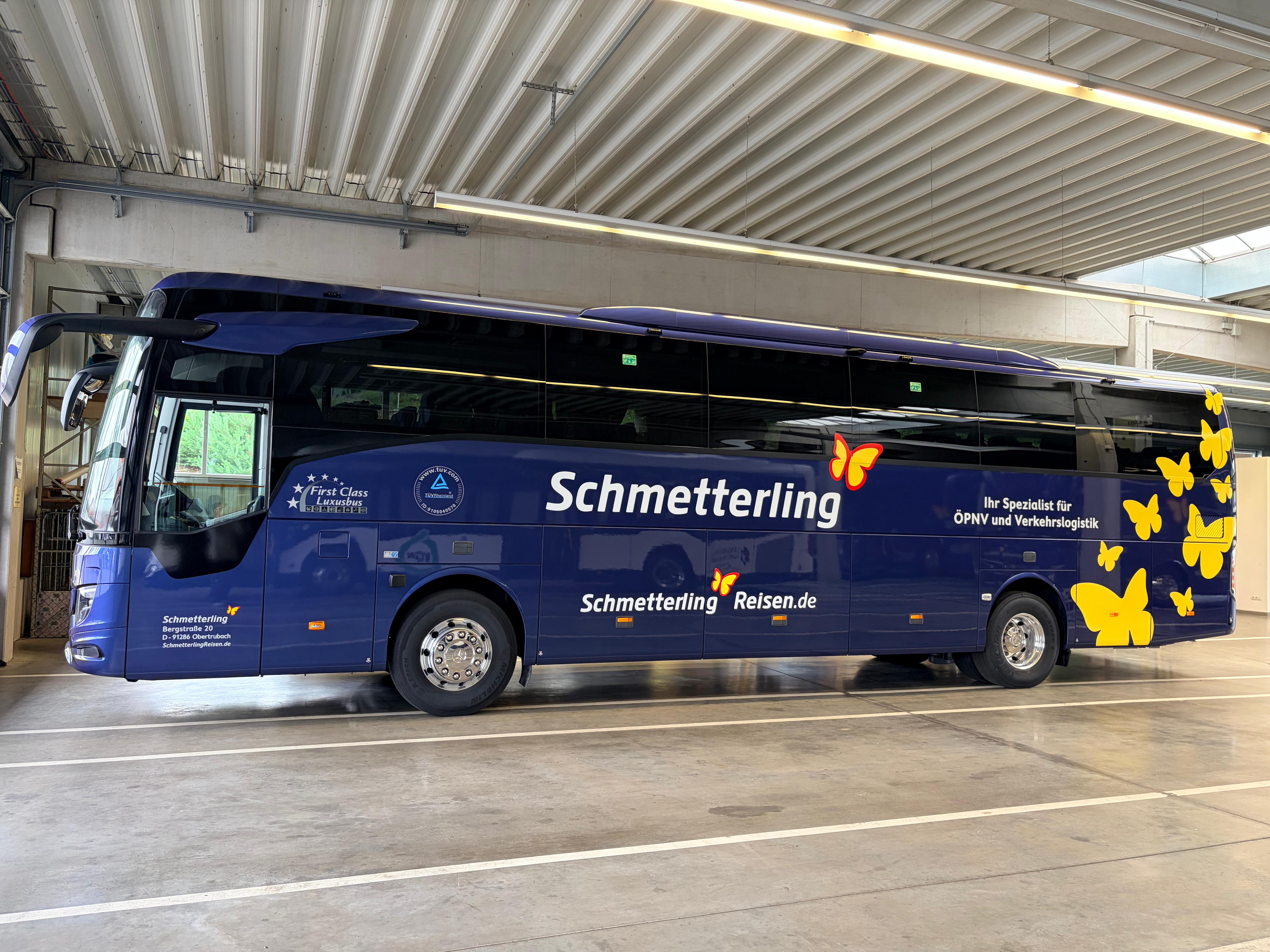 Dunkelblauer Reisebus von Schmetterling Reisen mit gelben Schmetterlingen in der Seitenansicht