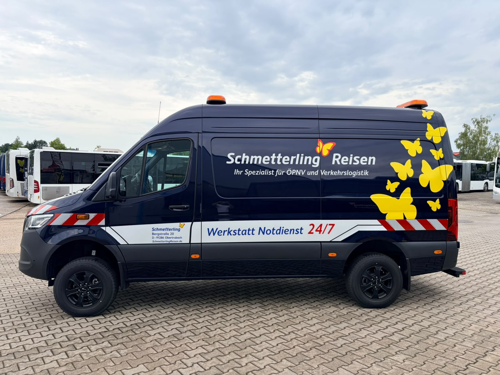 Dunkelblauer Schmetterling-Reisen-Werkstattwagen mit gelben Schmetterlingen und Notdienst-Beschriftung