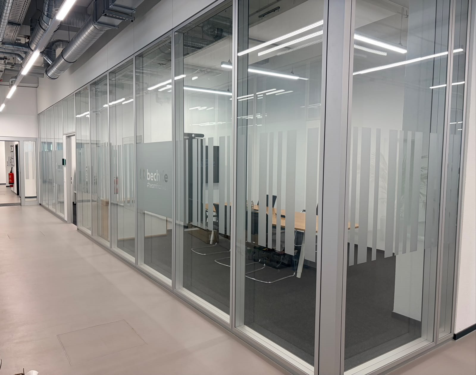 Langer Büroflur mit Sichtschutzstreifen auf gläsernen Trennwänden